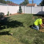 man touching up sod in a backyard