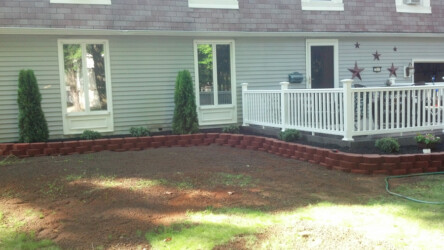 Red pavers around the back porch of a green house.