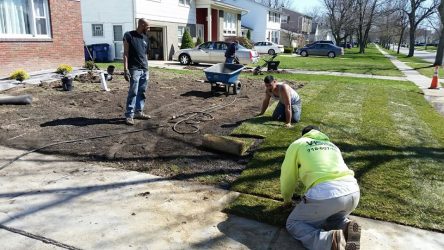 men planting mulch in a front yard